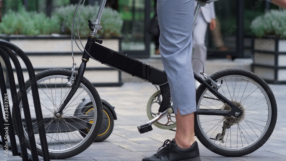 Fototapeta premium Man getting off bicycle on sidewalk at downtown. Male legs with bike closeup.