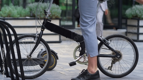 Man getting off bicycle on sidewalk at downtown. Male legs with bike closeup.