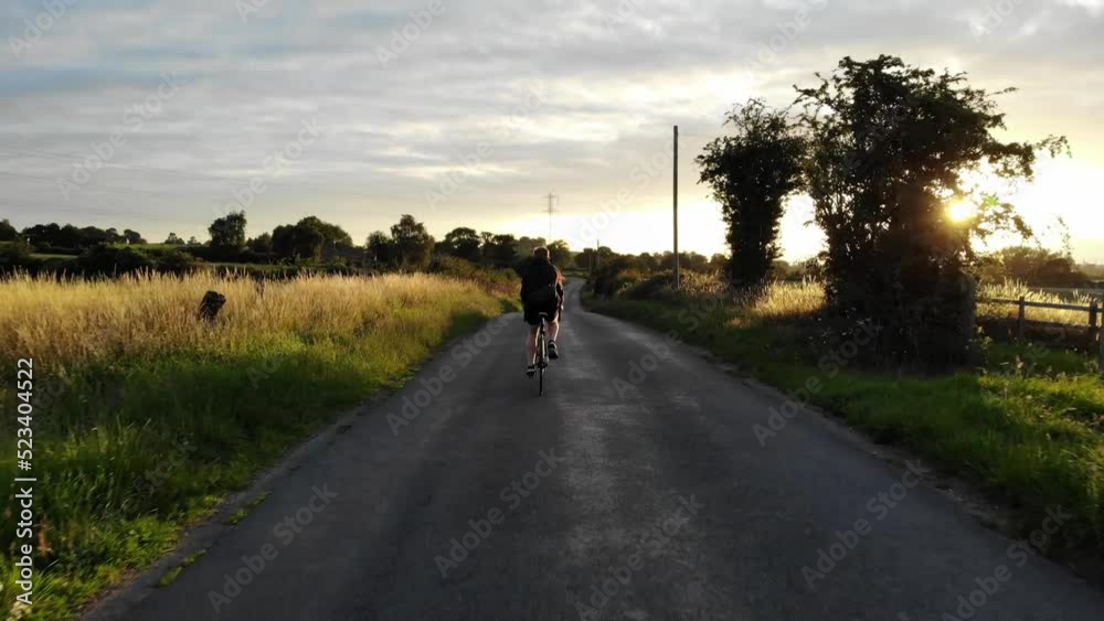 person riding a bicycle down a country road at sunset person riding a bicycle down a country road at sunset