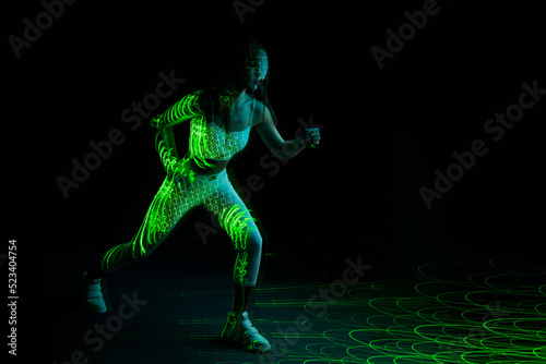 Woman in futuristic costume. Female posing in glasses of virtual reality. Augmented reality game, future technology, AI concept. VR. Neon green light.