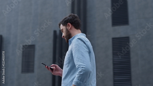Focused ceo texting message phone at modern glass building. Businessman calling photo