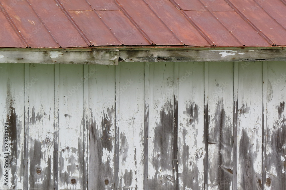weathered white washed building with red tin roof