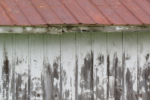 weathered white washed building with red tin roof