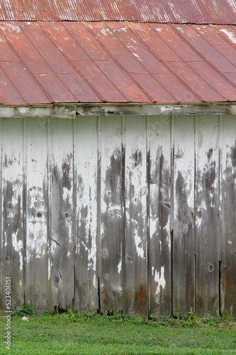 distressed white washed side of barn with red tin roof