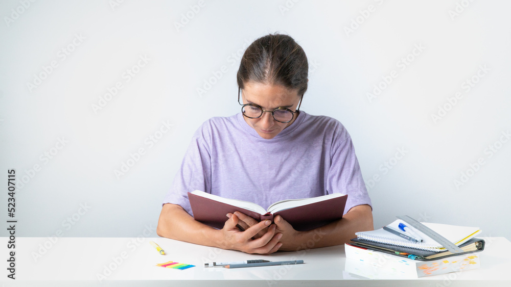 Student girl reading a book at the desk Student girl reading a book at the desk