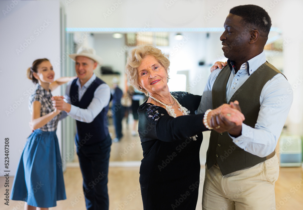 Elderly woman learning ballroom dancing in pair in dance studio Elderly woman learning ballroom dancing in pair in dance studio