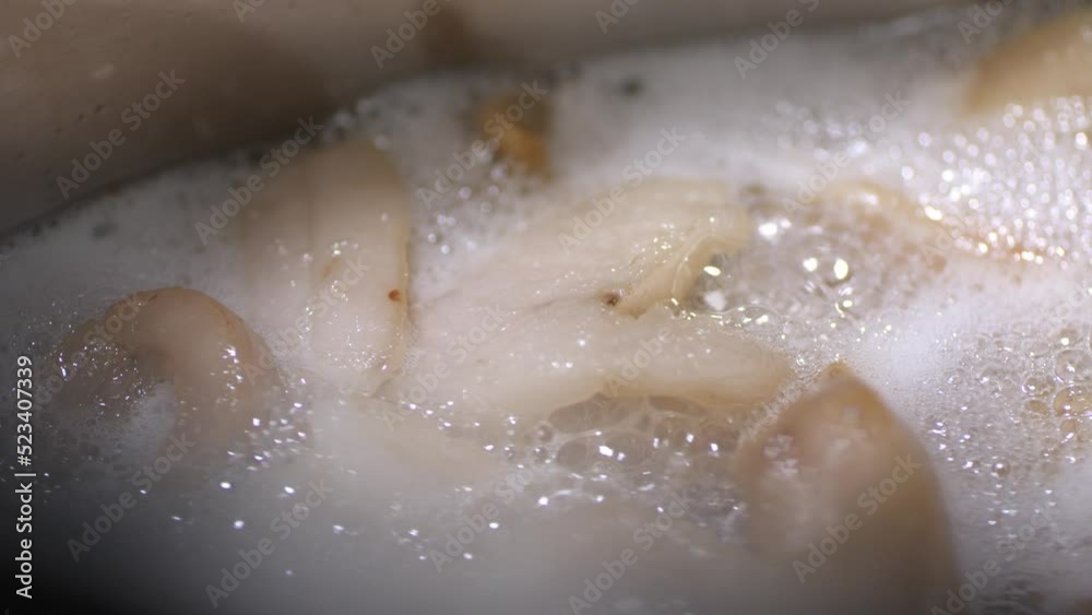Lard with a golden crust melts in a stainless steel pan with lots of bubbles. close-up camera moves.