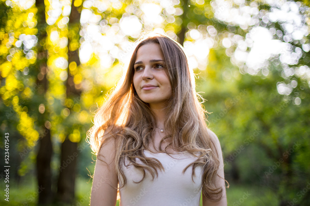 Beautiful young Russian girl dressed in a white dress, walks through the forest among the oaks in the rays of the sunset Beautiful young Russian girl dressed in a white dress, walks through the forest among the oaks in the rays of the sunset