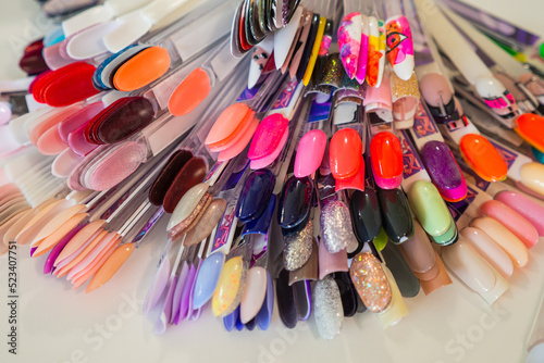 Different colorful manicure samples with coloured paintings on a palette in beauty salon. Multicolor vibrant set of false nails