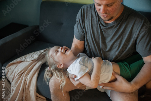 Foto dad has fun playing with his child at home on the couch, tickling him