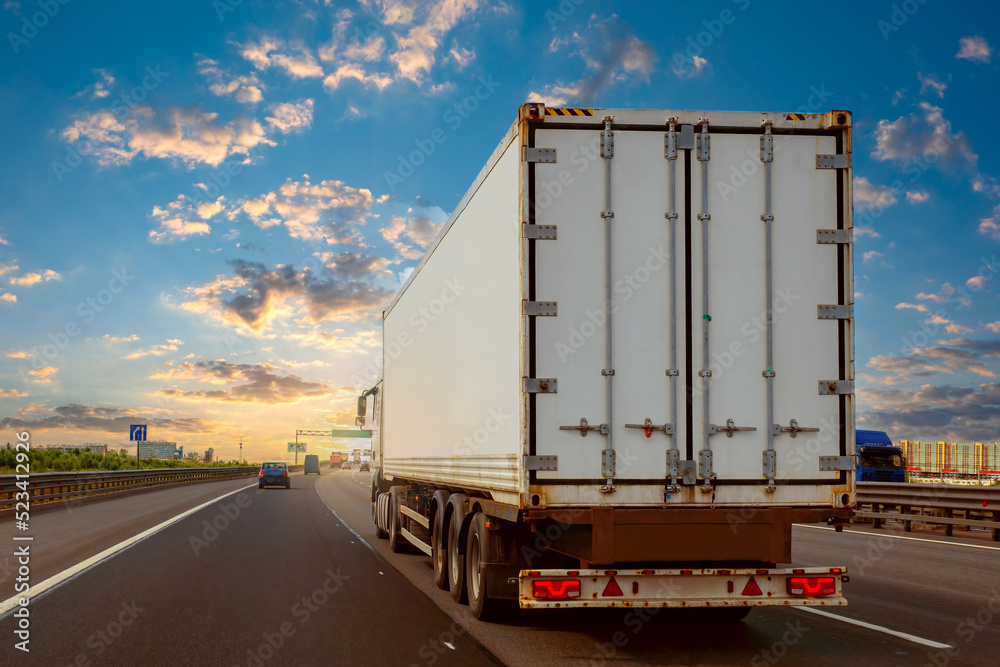 Truck on highway. Lorry with white trailer. Expressway with cars and big van. Transportation of goods with lorry. Road freight transportation. Concept - work as truck driver. Truck business.