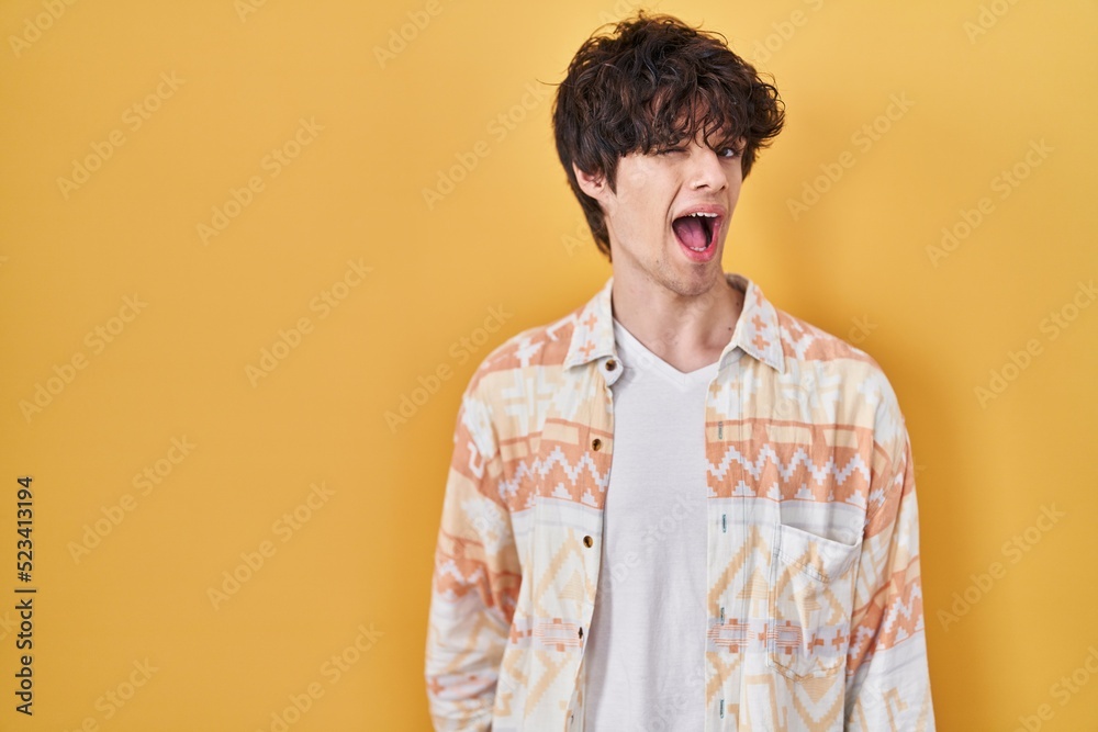 Young man wearing casual summer shirt winking looking at the camera with sexy expression, cheerful and happy face. Young man wearing casual summer shirt winking looking at the camera with sexy expression, cheerful and happy face.