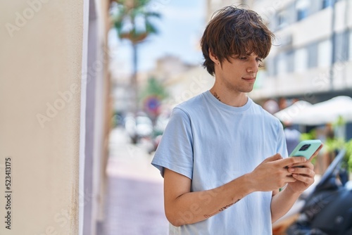 Young blond man using smartphone with serious expression at street