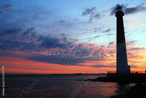 The Barnegat Lighthouse on the Jersey shore stands tall against the glowing sky at sunrise photo