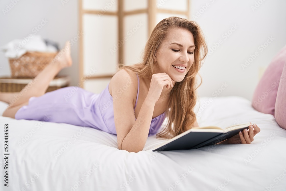 Young blonde woman reading book lying on bed at bedroom Young blonde woman reading book lying on bed at bedroom