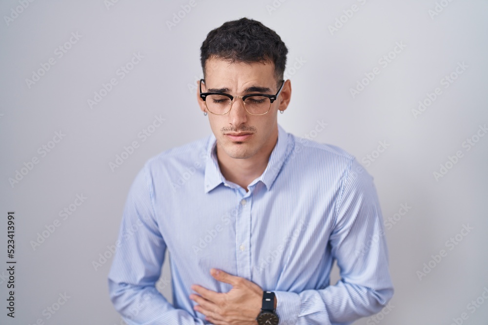 Handsome hispanic man wearing business clothes and glasses with hand on stomach because nausea, painful disease feeling unwell. ache concept. Handsome hispanic man wearing business clothes and glasses with hand on stomach because nausea, painful disease feeling unwell. ache concept.