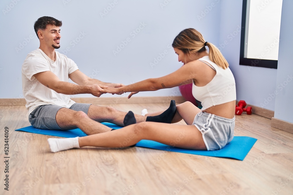 Young man and woman couple smiling confident stretching at sport center