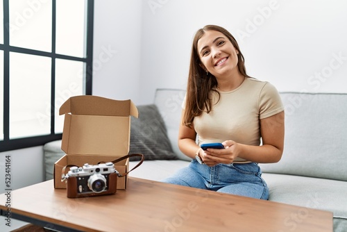 Young hispanic woman using smartphone reciving order at home photo