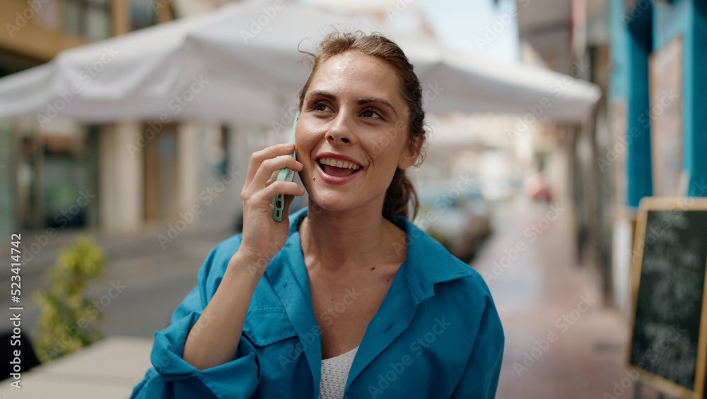 Young woman smiling confident talking on the smartphone at street