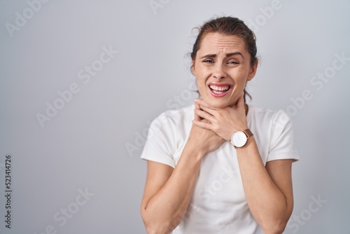 Beautiful brunette woman standing over isolated background shouting suffocate because painful strangle. health problem. asphyxiate and suicide concept.