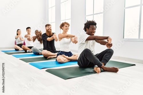 Group of young people smiling happy stretching at sport center.