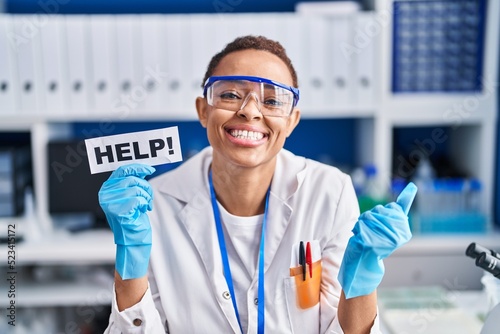 Beautiful african american woman working at scientist laboratory asking for help screaming proud, celebrating victory and success very excited with raised arms