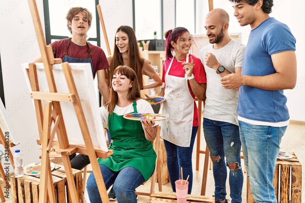 Fototapeta premium Group of young paint students smiling happy and looking draw of partner at art studio.