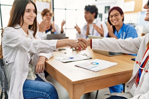 Group of doctor smiling and clapping to partners handshake in a medical meeting at the clinic office.