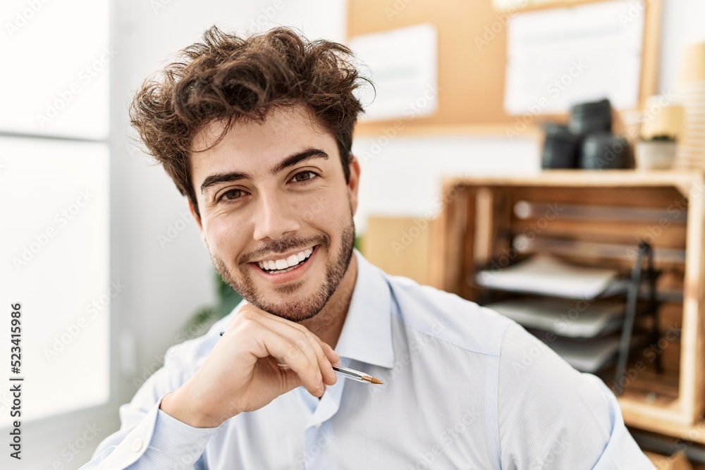 Naklejka premium Young hispanic businessman smiling happy working at the office.