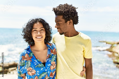 Young beautiful couple smiling happy and hugging standing at the beach.