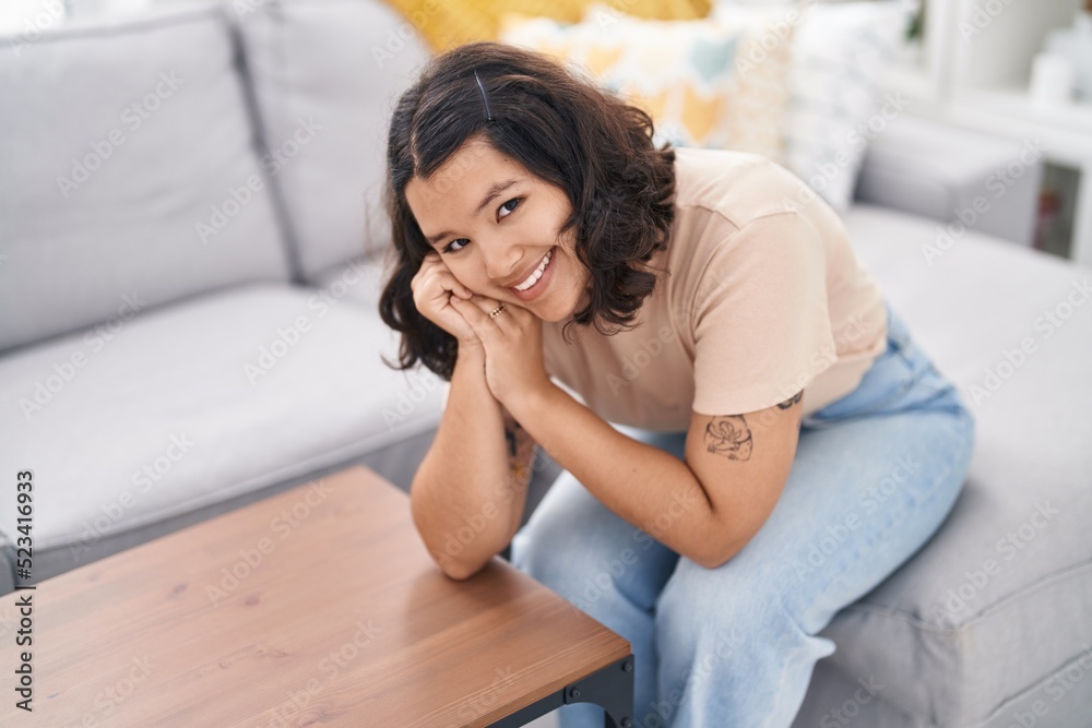 Young woman smiling confident sitting on sofa at home Young woman smiling confident sitting on sofa at home