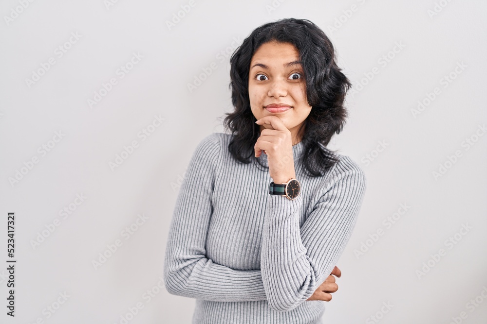 Hispanic woman with dark hair standing over isolated background thinking worried about a question, concerned and nervous with hand on chin Hispanic woman with dark hair standing over isolated background thinking worried about a question, concerned and nervous with hand on chin