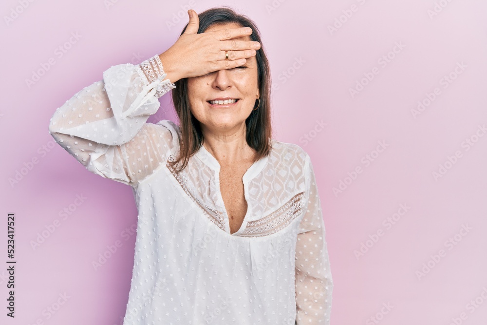 Middle age hispanic woman wearing casual clothes smiling and laughing with hand on face covering eyes for surprise. blind concept. Middle age hispanic woman wearing casual clothes smiling and laughing with hand on face covering eyes for surprise. blind concept.