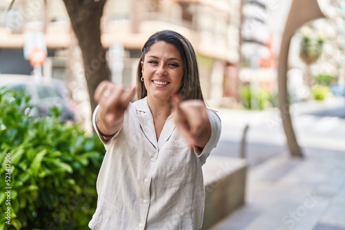 Young hispanic woman smiling confident pointing with fingers at street