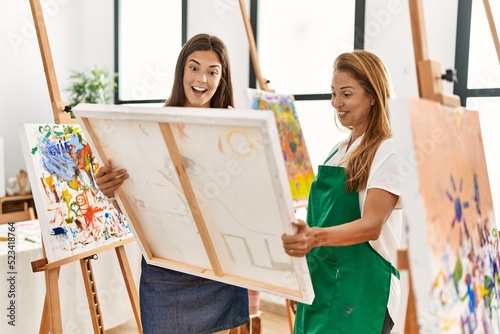 Mother and daughter smiling confident looking draw canvas at art studio