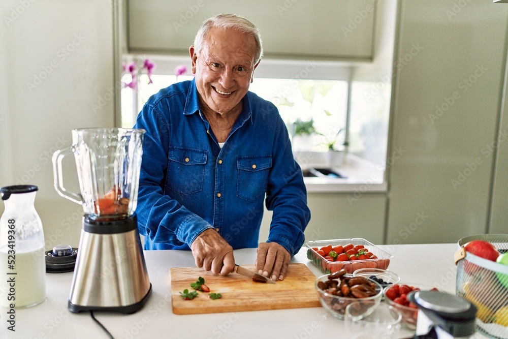 Senior man smiling confident cutting datil at kitchen Senior man smiling confident cutting datil at kitchen