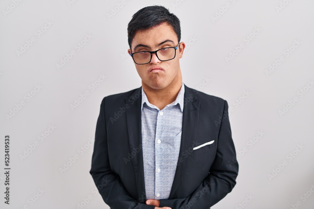 Young hispanic man with down syndrome wearing business style with hand on stomach because indigestion, painful illness feeling unwell. ache concept. Young hispanic man with down syndrome wearing business style with hand on stomach because indigestion, painful illness feeling unwell. ache concept.