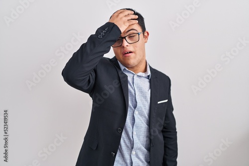 Young hispanic man with down syndrome wearing business style surprised with hand on head for mistake, remember error. forgot, bad memory concept.