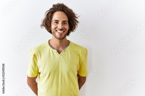 Young hispanic man standing over isolated background with a happy and cool smile on face. lucky person.