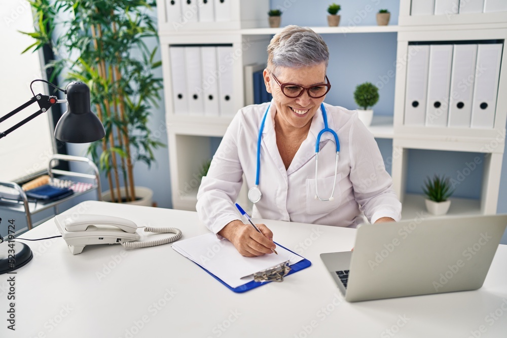 Middle age woman wearing doctor uniform working at clinic Middle age woman wearing doctor uniform working at clinic