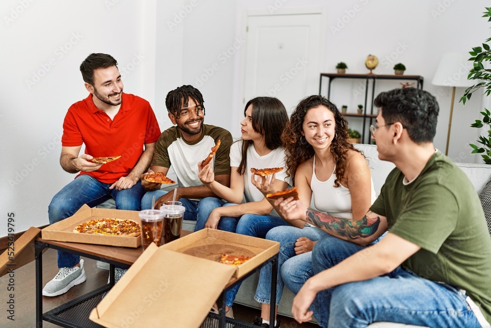Group of young friends smiling happy eating italian pizza sitting on the sofa at home. Group of young friends smiling happy eating italian pizza sitting on the sofa at home.