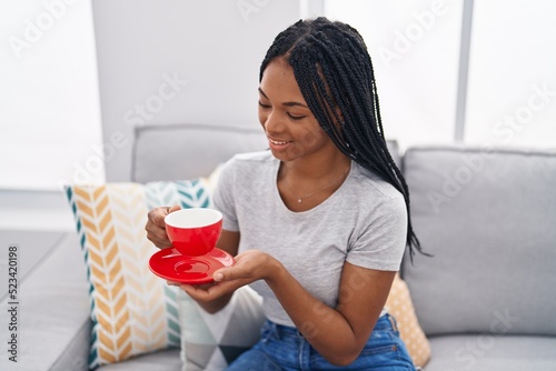 African american woman listening to music drinking coffee at home