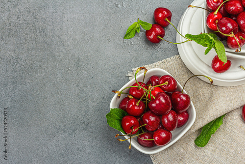 Ripe sweet cherries with fresh mint leaves, traditional summer fruits. Trendy stands, vintage napkin