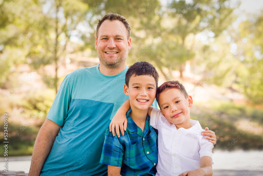 Outdoor portrait of mixed race Chinese and Caucasian brothers and their father.