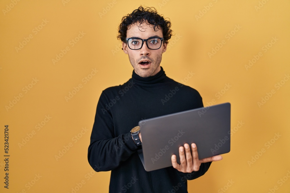 Hispanic man working using computer laptop scared and amazed with open mouth for surprise, disbelief face Hispanic man working using computer laptop scared and amazed with open mouth for surprise, disbelief face