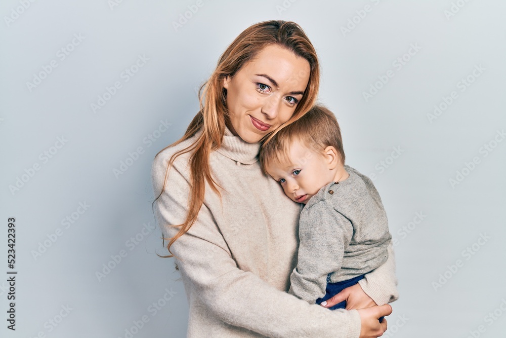 Young caucasian woman holding and hugging her son with love. Family of two bonding together. Mother holding infant toddler