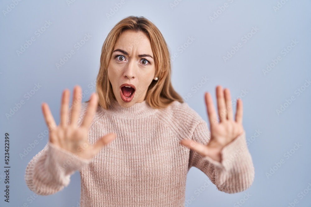 Hispanic woman standing over blue background doing stop gesture with hands palms, angry and frustration expression Hispanic woman standing over blue background doing stop gesture with hands palms, angry and frustration expression