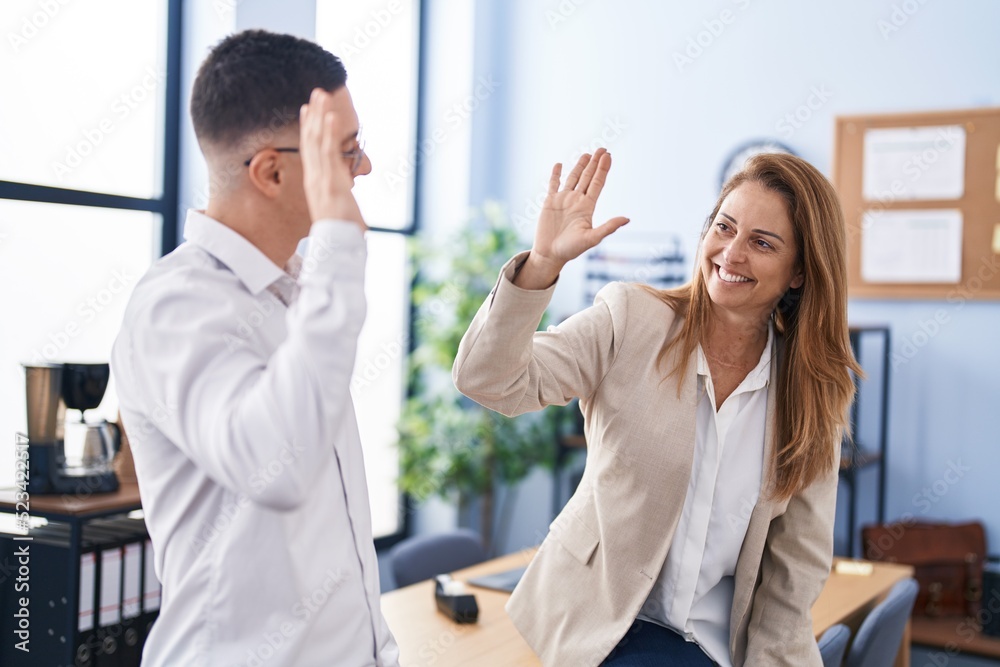 Man and woman business workers high five with hands raised up at office Man and woman business workers high five with hands raised up at office