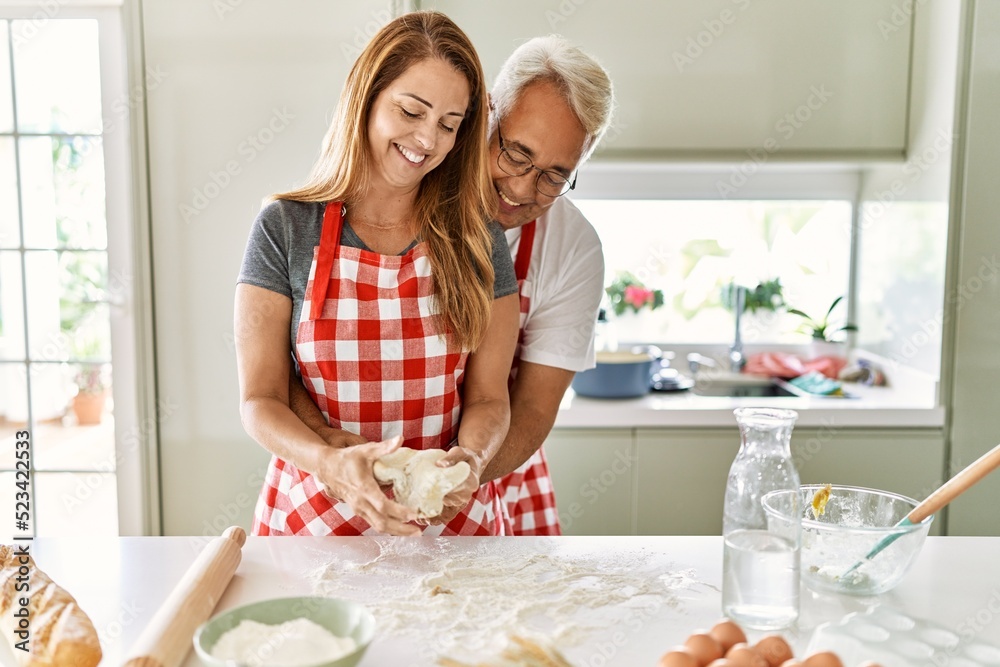 Middle age hispanic couple smiling happy and hugging cooking bread at the kitchen. Middle age hispanic couple smiling happy and hugging cooking bread at the kitchen.