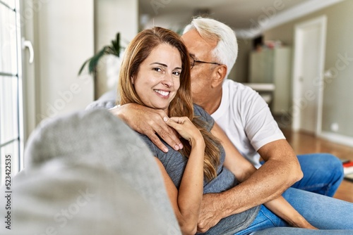 Middle age hispanic couple smiling happy and hugging sitting on the sofa at home. © Krakenimages.com